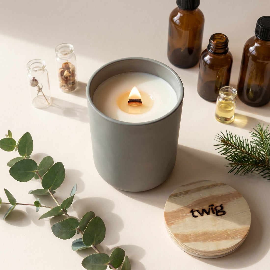 Twig wood wick candle burning beside fragrance oil vials, eucalyptus and fir — small-batch clean fragrance made in Canada
