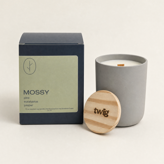 Gray candle with wooden lid and 'twig' branding next to its packaging on a white background