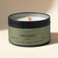 Candle in a container labeled 'Mossy' by twig fragrance co. on a beige background